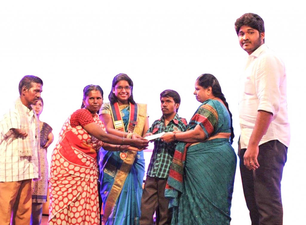 A donor hands over a cheque to a parent to sponsor the education of a student at the Vidiyal programme. 