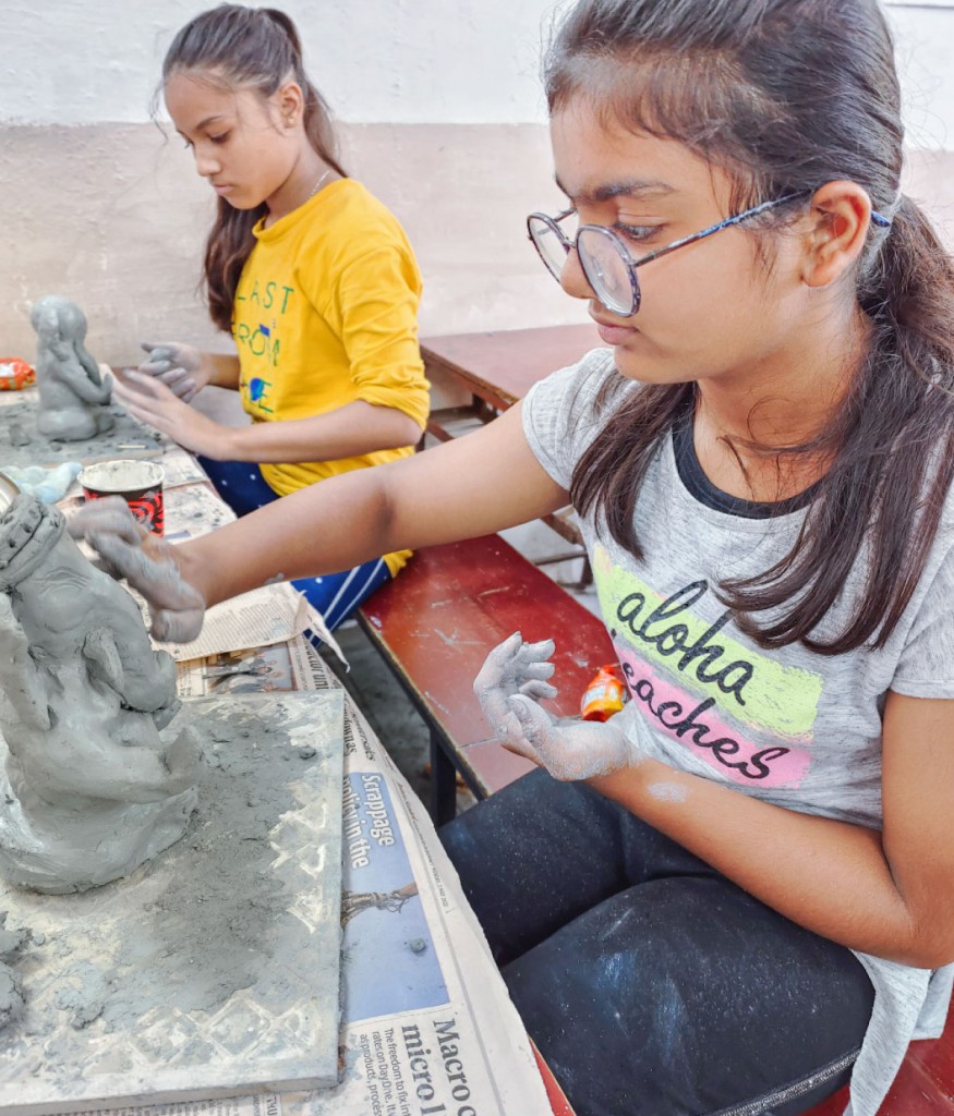 Young girls sculpting idols from organic clay.