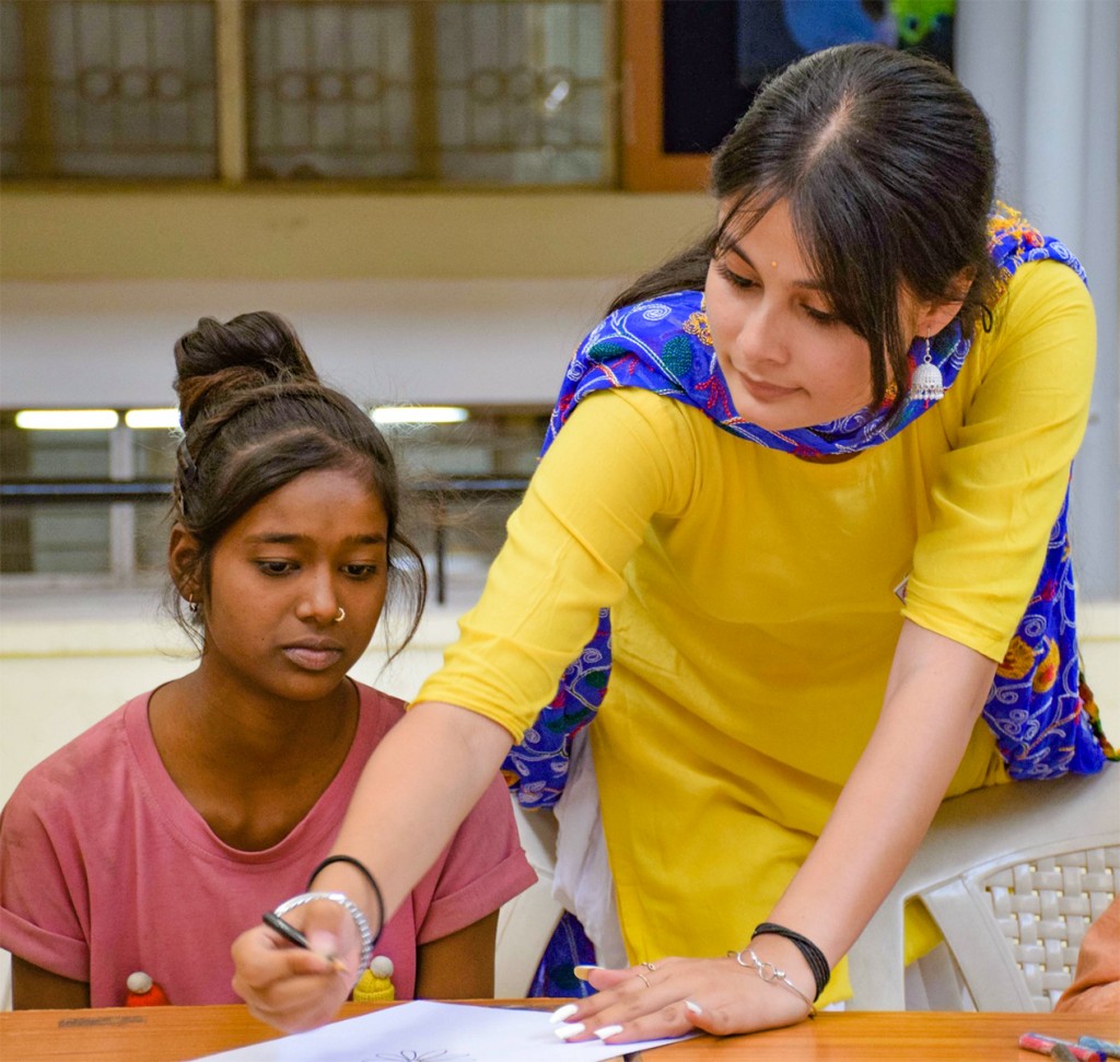 Club president Khushi Srivastava teaching a girl to sketch.