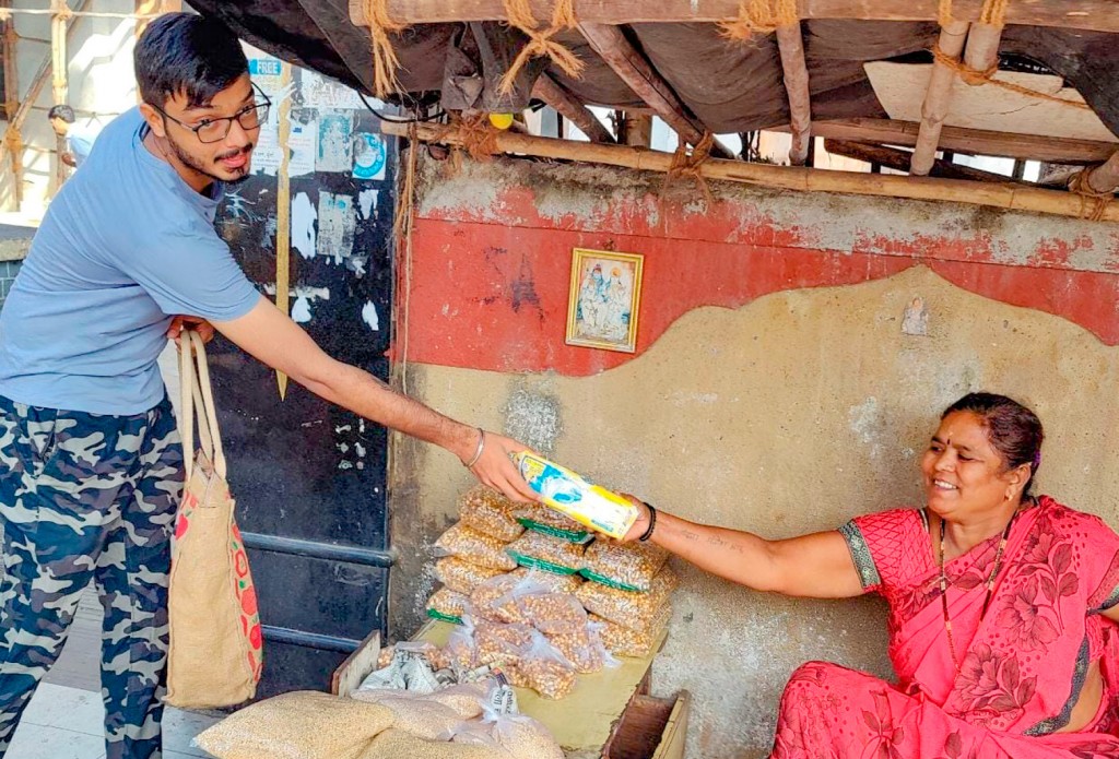 A Rotaractor gives a sanitary napkin pack to a woman.