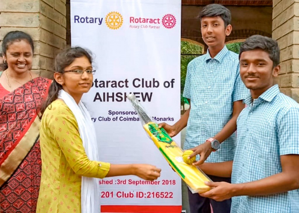 A Rotaractor presents a cricket bat and ball, as part of sports equipment the club donated to the school. 