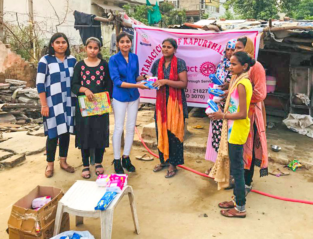 Club members distribute sanitary napkins to women living in the slums.