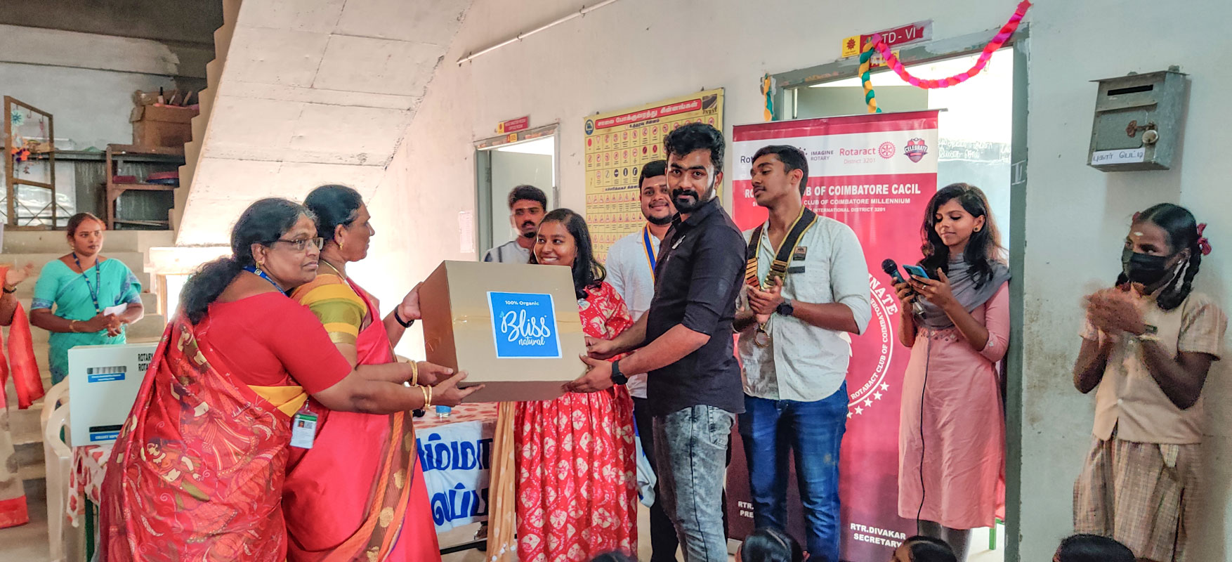 Rotaractors hand over a carton of sanitary napkins for distribution at a school.