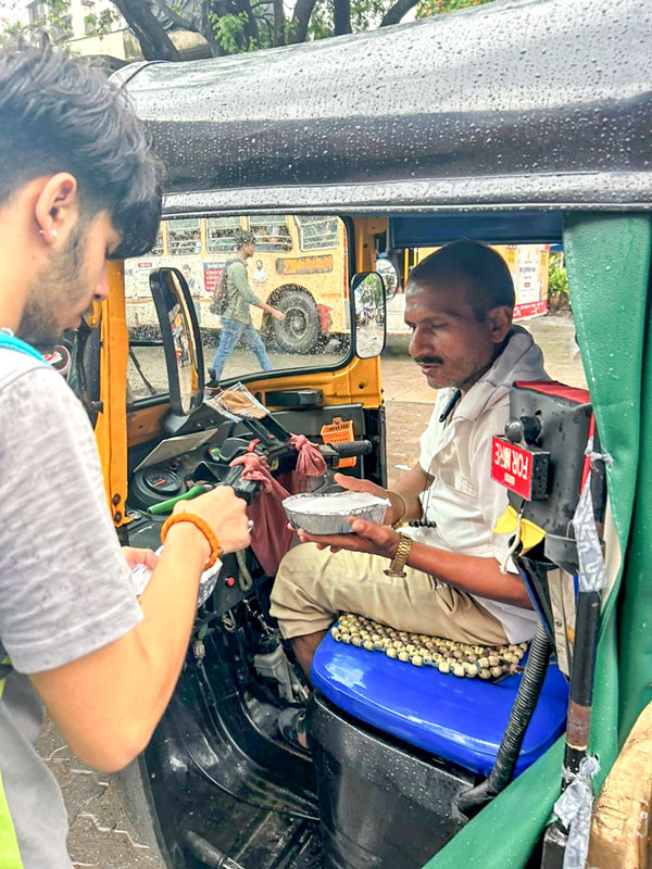 A Rotaractor gives a food packet to an autorickshaw driver. 