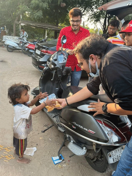 A Rotaractor distributes food packet to a child on the sidelines of WASH session.